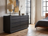 Conegliano 66-Inch Burnished Black 8-Drawer Dresser against a plaster wall in an industrial loft bedroom