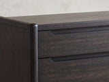 Close-up of the Conegliano 66-Inch Burnished Black 8-Drawer Dresser: the carved finger channel and the rounded corner post in burnished black ash