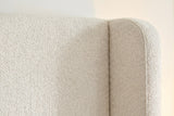 Close-up of the Conversano bed where the cream boucle wing meets the headboard panel along a plain seam