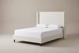 The Conversano bed in cream white boucle with a white mattress and pillows (not included), three-quarter view on a light studio backdrop