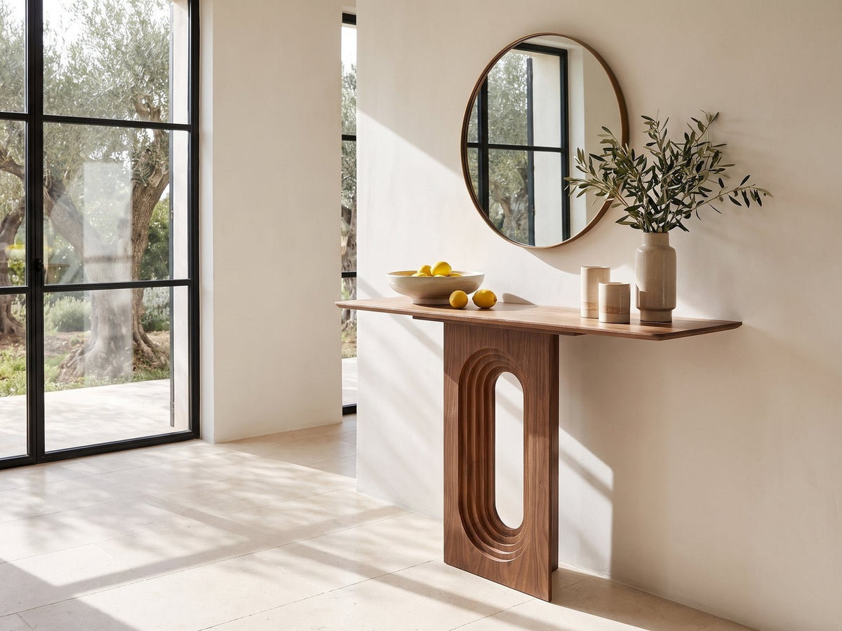 Corato Walnut Veneer Pedestal Console Table under a round bronze mirror beside a glass wall onto an olive garden in a sunlit villa