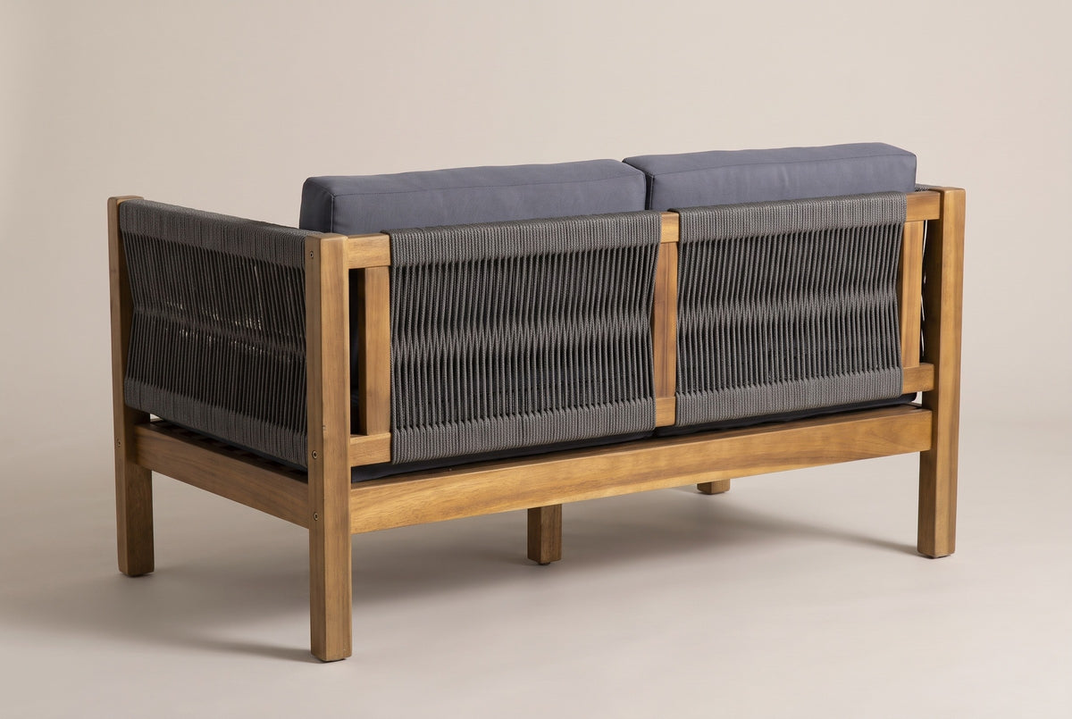 The Corleone loveseat from behind: two rope-woven back panels around a central acacia post, a woven arm and square legs