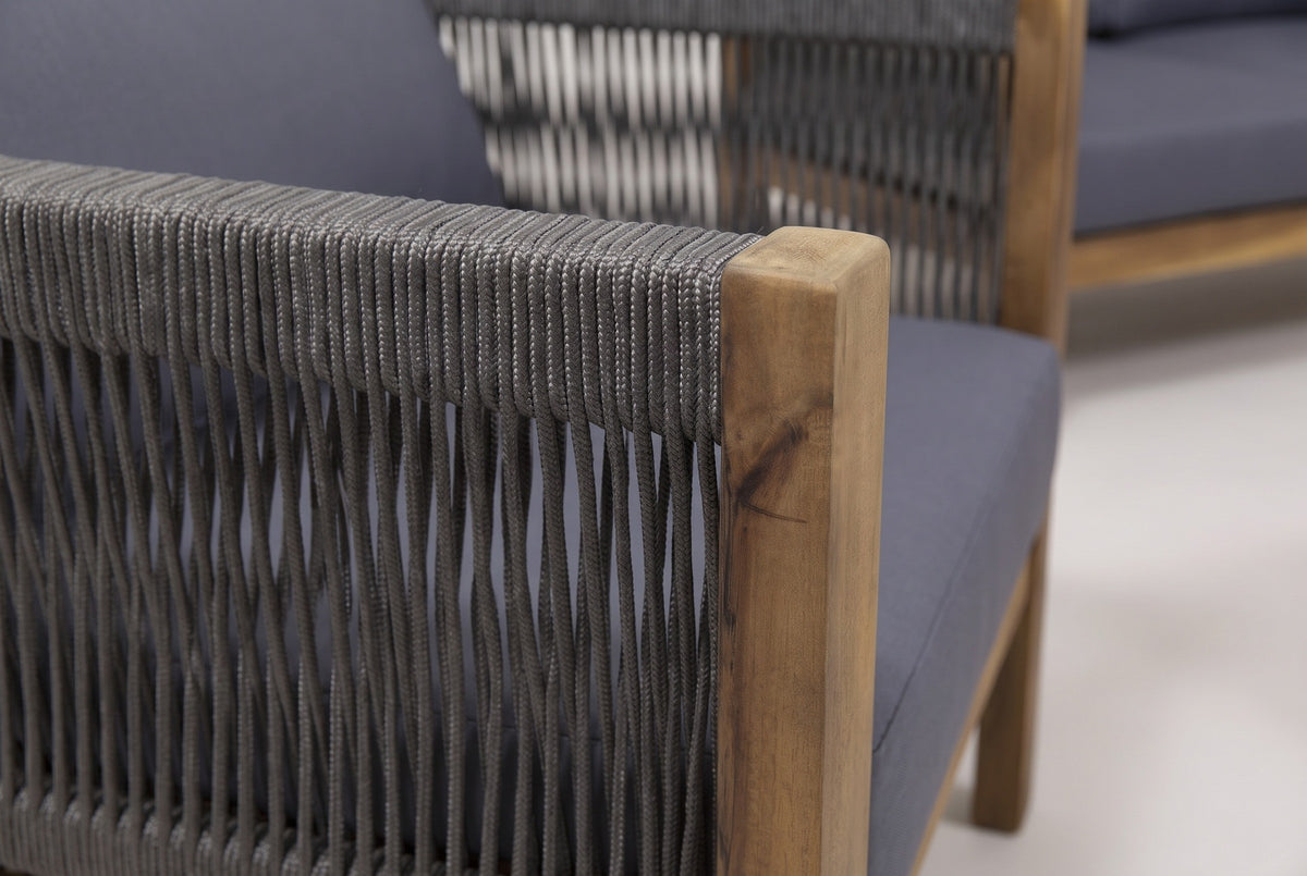 Close-up of a Corleone club chair arm: braided dark grey rope wrapped over the rail beside the square acacia front post, with the seat cushion