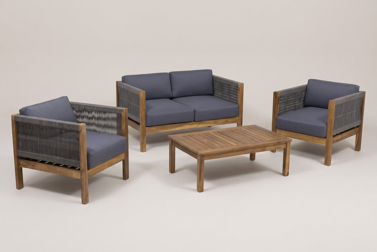 The Corleone four-piece set: loveseat, two club chairs and a slatted coffee table in acacia with dark grey rope and cushions, on a studio backdrop