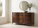 Cormons 66-Inch Dark Cherry and Burl 9-Drawer Dresser under a round bronze mirror in a villa bedroom