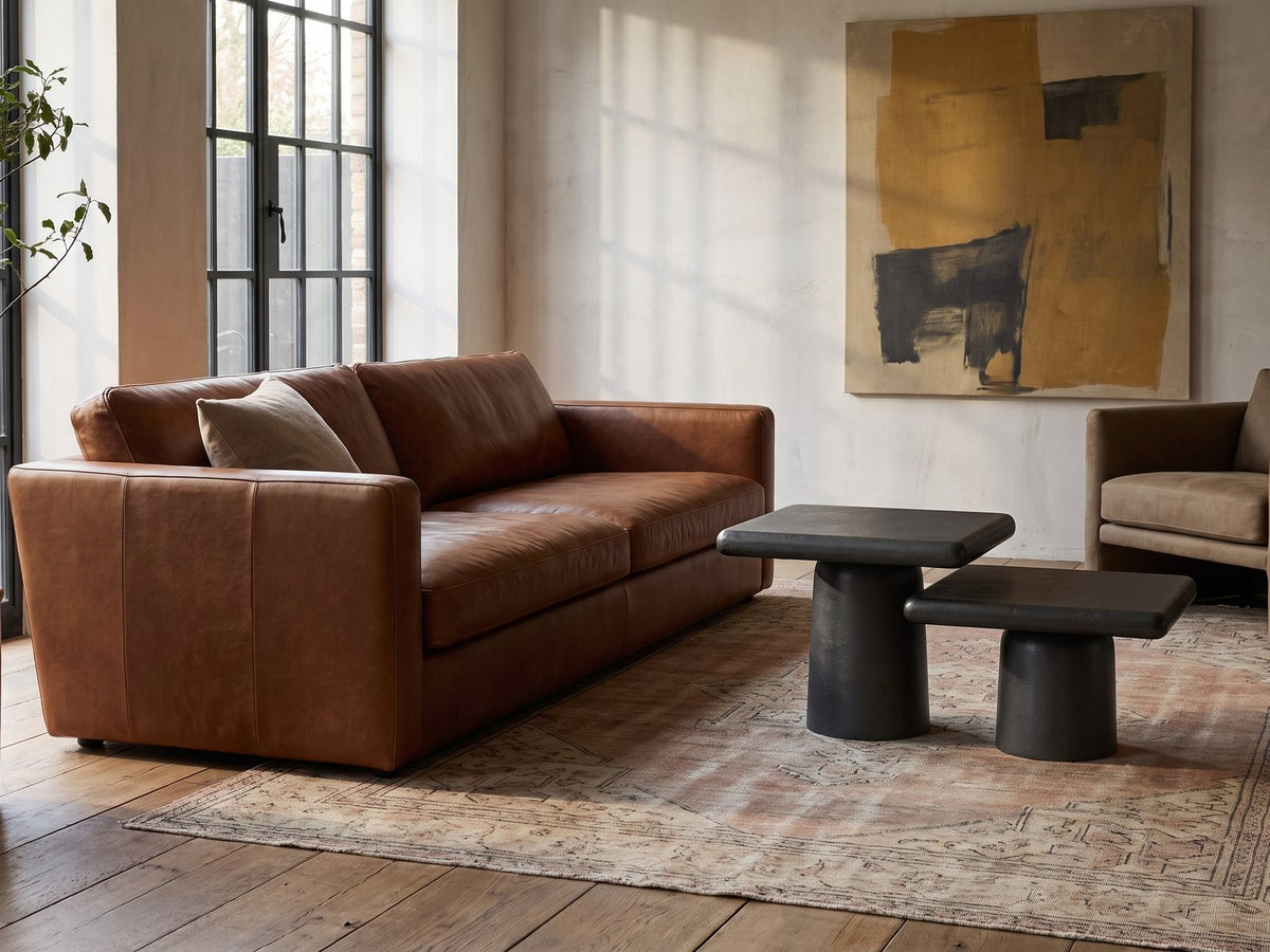 Cortona Cast Aluminum Pedestal Coffee Tables, Set of 2 on a vintage rug in front of a leather sofa in an industrial loft