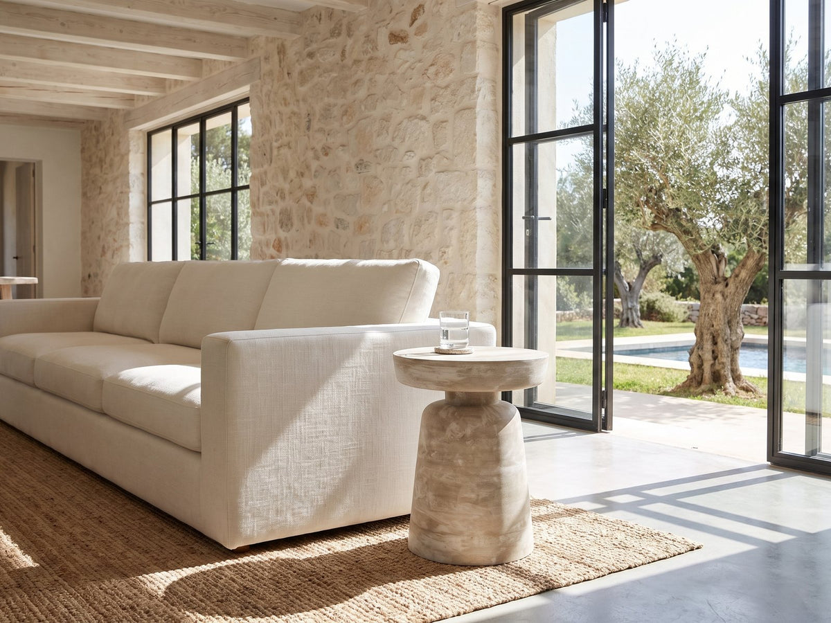 Craco Whitewashed Mango Pedestal Side Table beside a linen sofa in a poolside villa