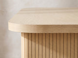 Close-up of the Cropani 69-Inch Rectangular Fluted Dining Set with 4 Arm Chairs: the rounded corner of the oak-veneer top above a fluted panel leg