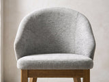 Close-up of the Crucoli 47-Inch Round Walnut-Finish Dining Set with 4 Chairs: the curved shell back and padded seat of a chair in light grey fabric