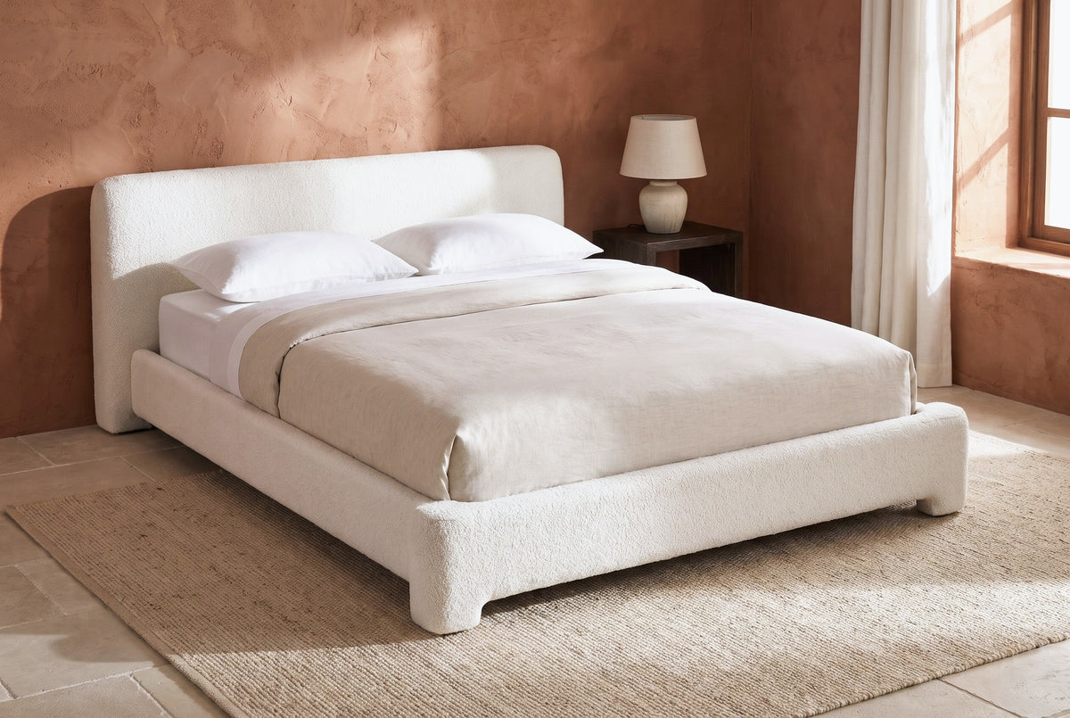 Cupello platform bed against a terracotta clay plaster wall in a Santa Fe bedroom with a limestone floor and a wool rug