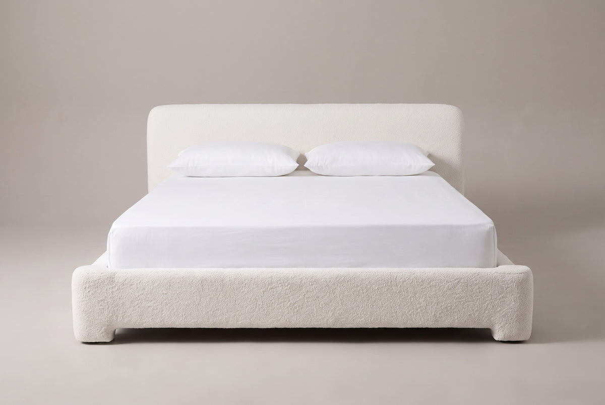 Cupello platform bed in white boucle with a white mattress and pillows (not included), front view