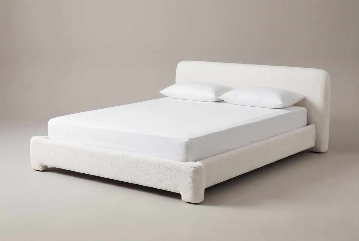 The Cupello platform bed in white boucle with a white mattress and pillows (not included), three-quarter view on a light studio backdrop