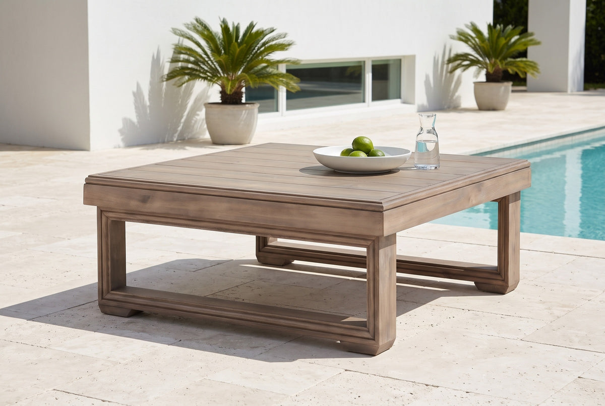 Custonaci acacia coffee table on ivory travertine by a pool in Sarasota, Florida, a white stucco wall and potted sago palms behind (bowl, limes and carafe not included)
