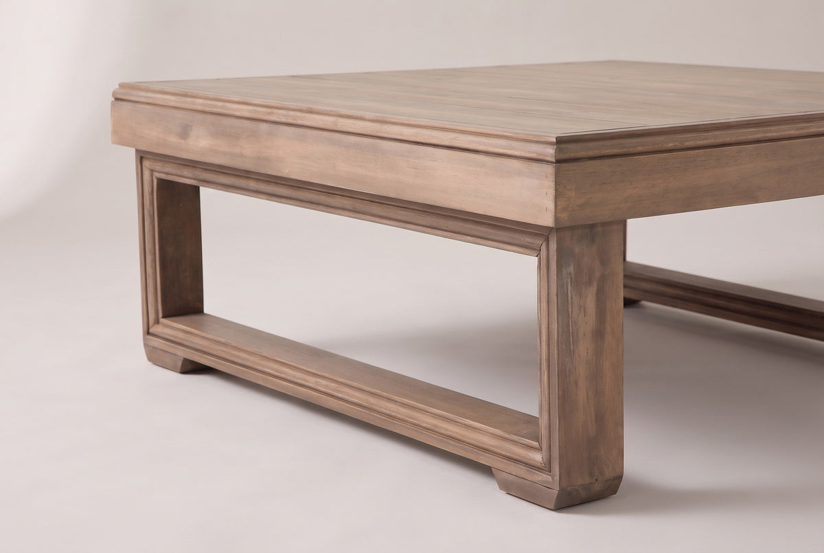 One sled frame of the Custonaci coffee table at floor level: square post, runner, moulded bead and block foot under the deep apron