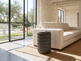 Cutigliano Cast Aluminum Carved Cylinder Side Table beside a linen sofa in a poolside villa