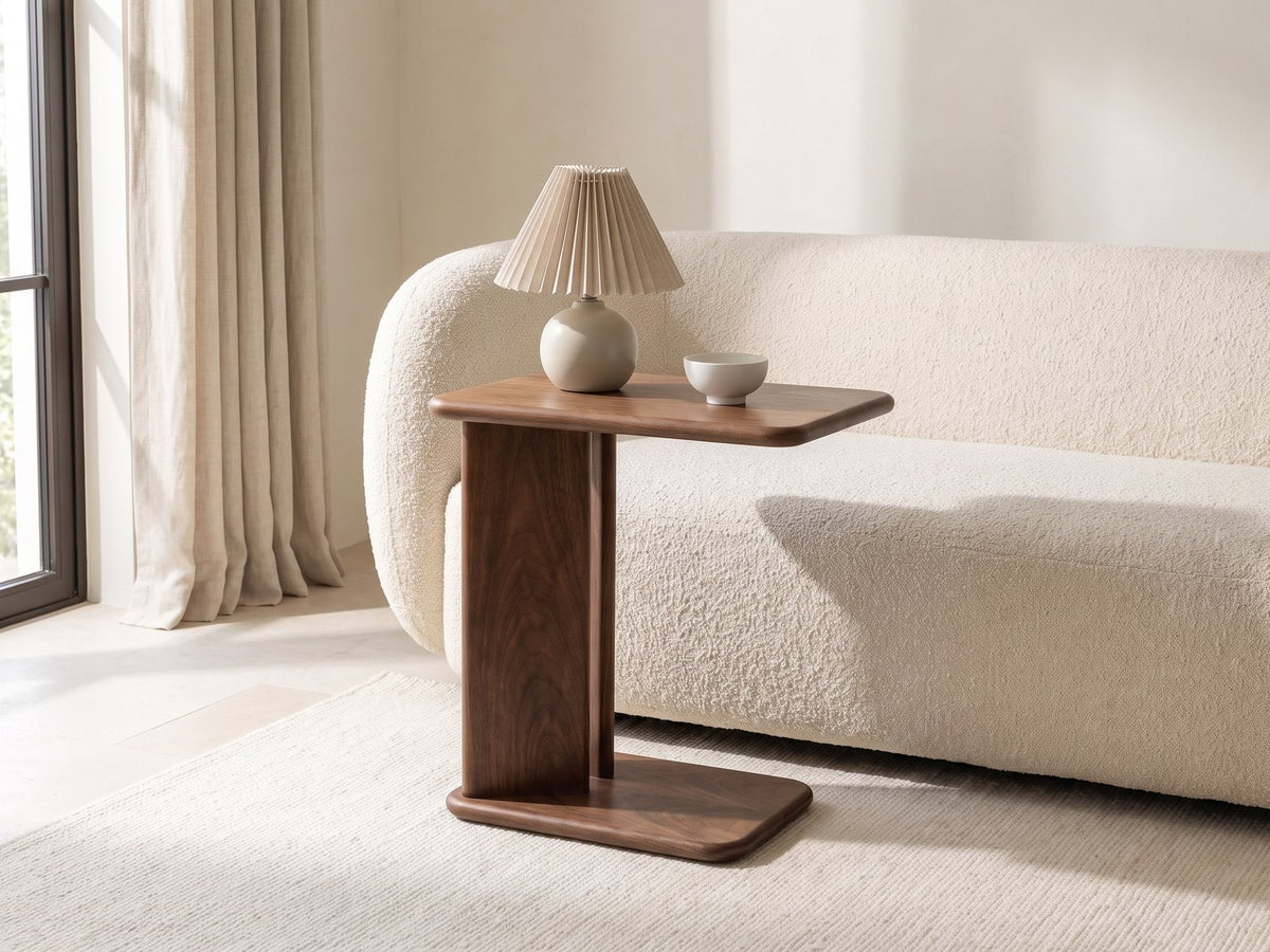 Cutrofiano Walnut Veneer C-Shaped Side Table with a lamp and a ceramic bowl beside a cream boucle sofa in a bright plaster room