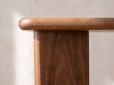 Close-up of the Cutrofiano Walnut Veneer C-Shaped Side Table: the rounded bullnose edge of the walnut top above the upright