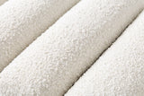 Close-up of the ivory white boucle on the Deruta bench: a nubby looped texture across three rounded channels