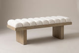 The Deruta bench in ivory white boucle on a wire-brushed wood frame, three-quarter view on a light studio backdrop
