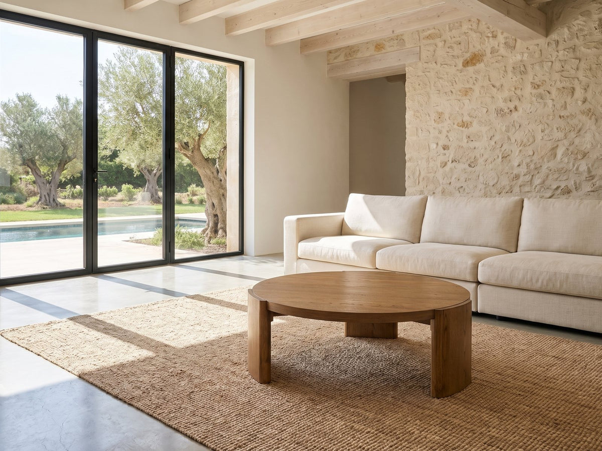 Dogliani 42-Inch Round Walnut-Stained Oak Veneer Coffee Table on a jute rug in front of a linen sofa in a poolside villa