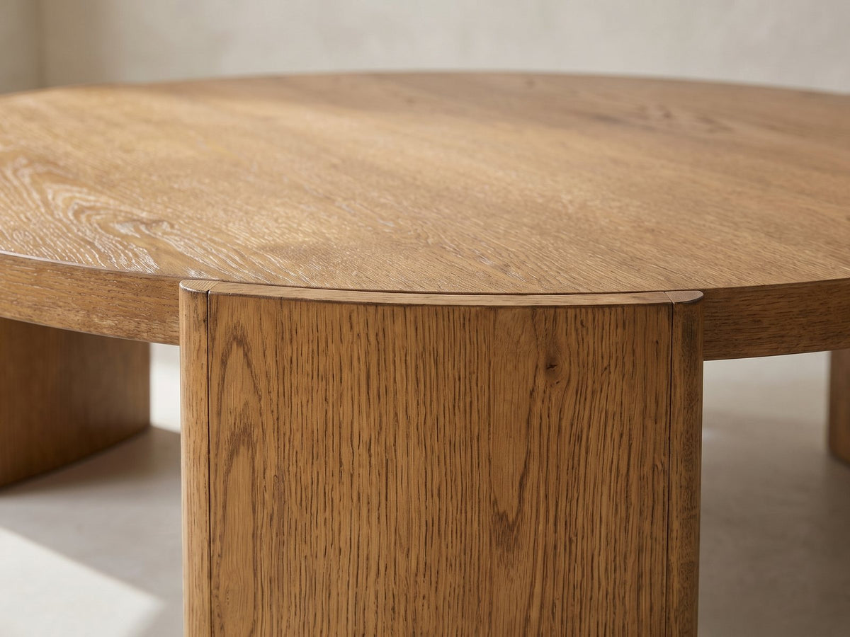 Close-up of the Dogliani 42-Inch Round Walnut-Stained Oak Veneer Coffee Table: a curved oak slab leg set flush into the edge of the round top