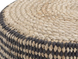 Close-up of the Dolceacqua Natural Braided Jute Round Pouf: the coiled jute braid of the top meeting the black and natural woven side
