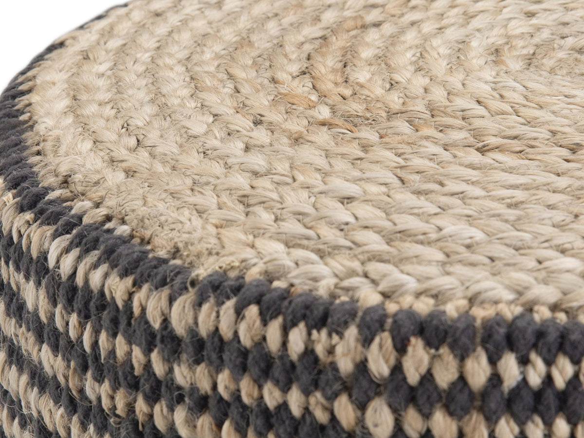 Close-up of the Dolceacqua Natural Braided Jute Round Pouf: the coiled jute braid of the top meeting the black and natural woven side