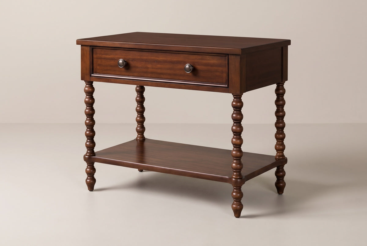 The Dorgali Morocco Brown nightstand with one wide drawer, two metal knobs, four turned bobbin legs and an open lower shelf, three-quarter view on a warm greige studio backdrop