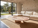 Elba Rosa Marble Coffee Table on a jute rug in front of a linen sofa in a poolside villa