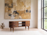 Erice Curved Mango Media Console seen from the side, under a large abstract painting in a bright living room