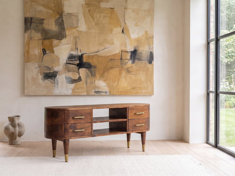 Erice Curved Mango Media Console seen from the side, under a large abstract painting in a bright living room