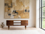 Erice Curved Mango Media Console under a large abstract painting in a bright living room