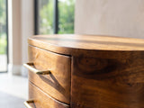 Close-up of the Erice Curved Mango Media Console: the rounded corner of the mango top and the curved drawer fronts below it