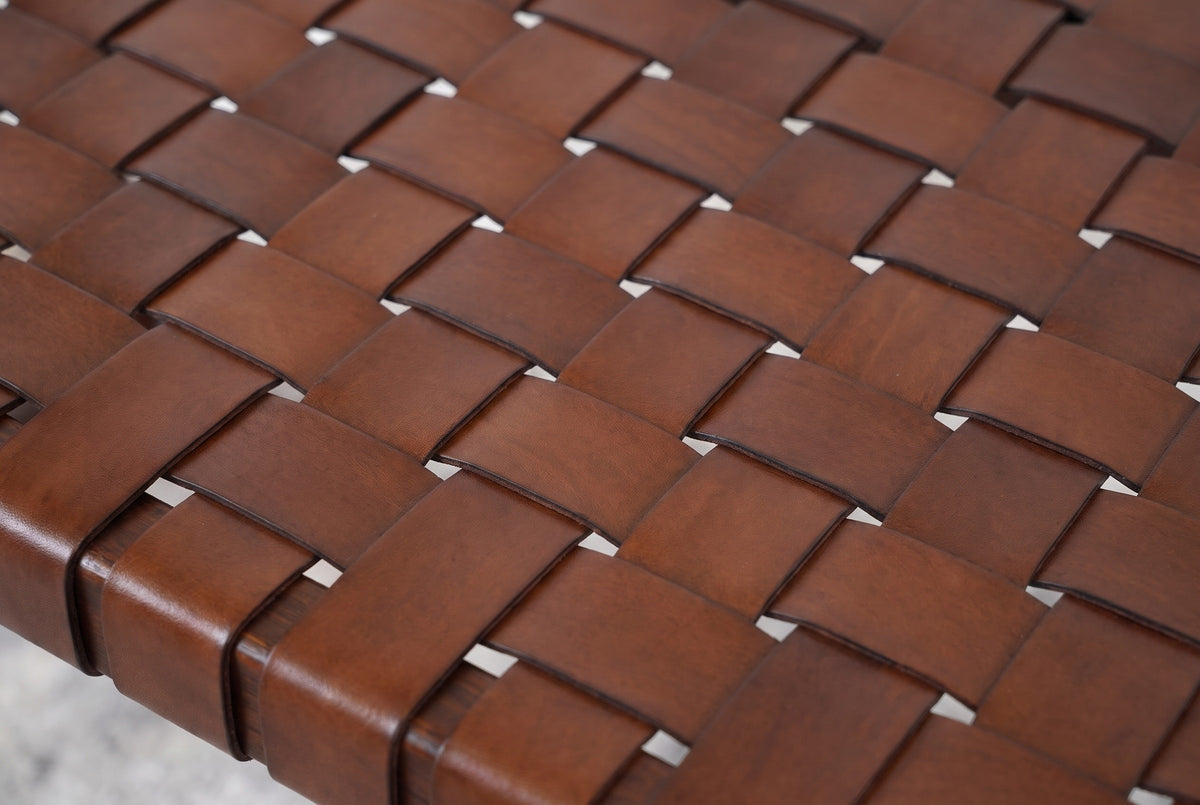 Close-up of the woven genuine leather seat of the Fasano bench: cognac-brown straps passing over two and under two