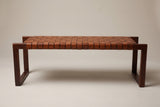 The Fasano bench, front view of the long side on a light studio backdrop: the row of leather strap loops and an end frame at each end