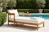 Favignana acacia chaise lounge on a limestone pool terrace at a Palm Beach villa, a clipped hedge and potted olive trees behind (side table not included)