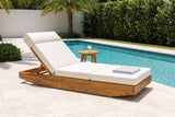 Ferla acacia chaise lounge beside a lap pool in Boca Raton, Florida, with a white stucco wall, pale stone pavers and palms (side table and towel not included)