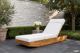 Ferla acacia chaise on a slate terrace in Dallas, Texas, with a pale stacked-stone wall, boxwood and an olive tree (side table not included)