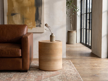Ferrandina Natural Wood Veneer Drum Side Table beside a leather sofa in an industrial loft