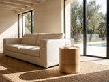 Ferrandina Natural Wood Veneer Drum Side Table beside a linen sofa in a poolside villa