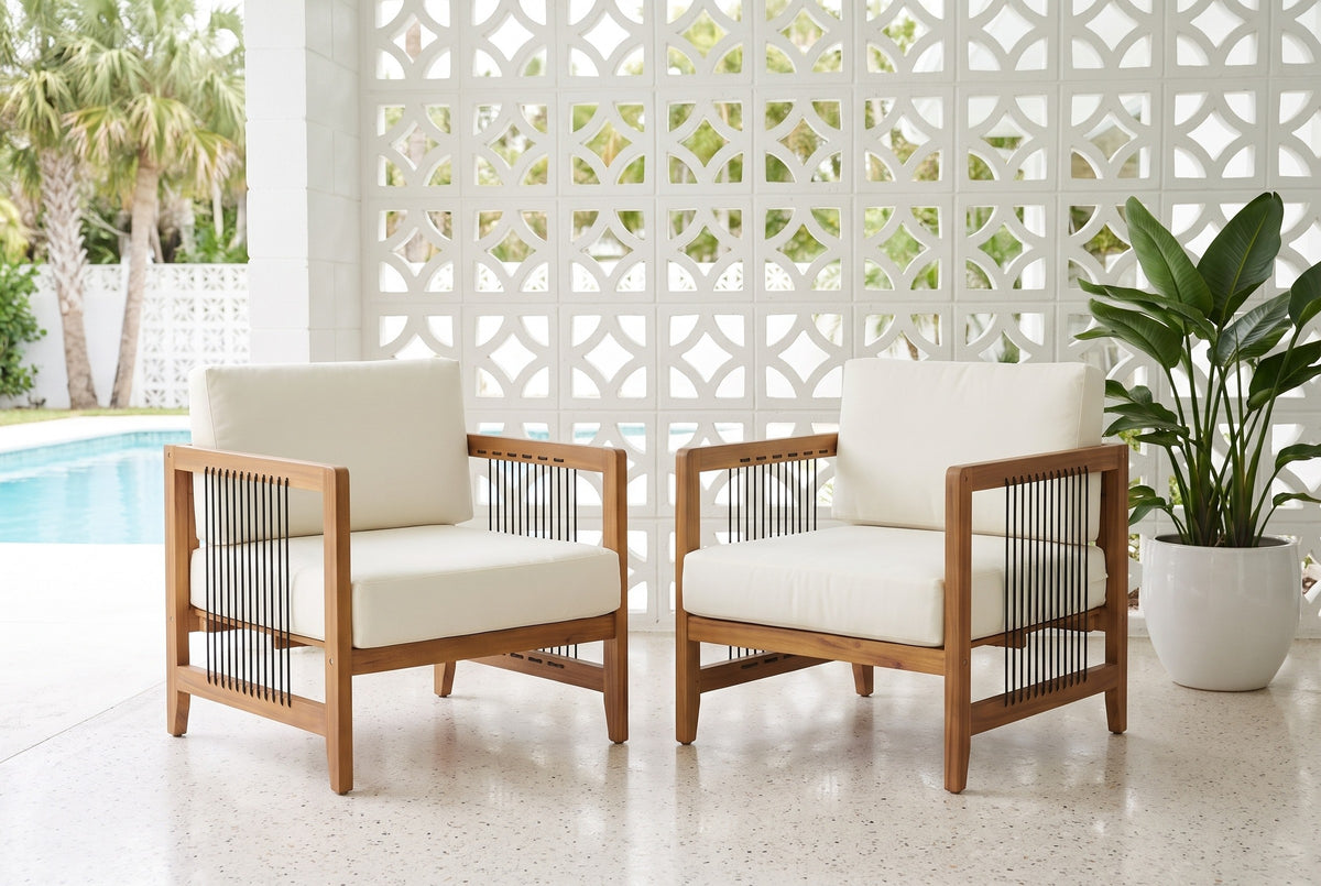 Two Ficarra acacia armchairs on a terrazzo lanai in front of a white breeze-block wall, a pool and palms beyond (planter not included)