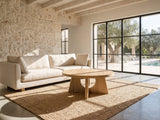 Fiesole Cerused Oak Veneer Round Pedestal Coffee Table on a jute rug in front of a linen sofa in a poolside villa
