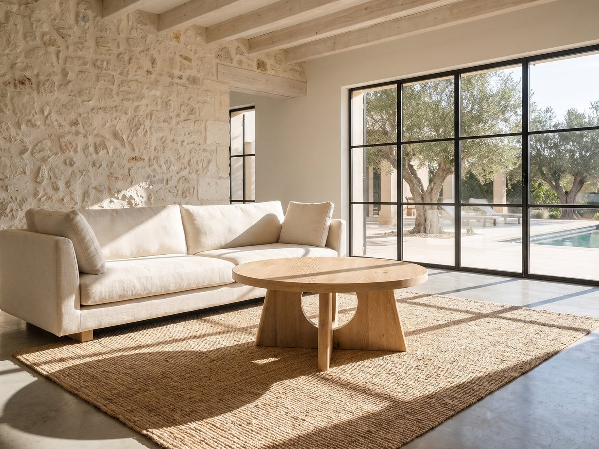 Fiesole Cerused Oak Veneer Round Pedestal Coffee Table on a jute rug in front of a linen sofa in a poolside villa