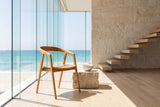 Filadelfia Sculpted Oak Wood Dining Arm Chair in an oceanfront glass house