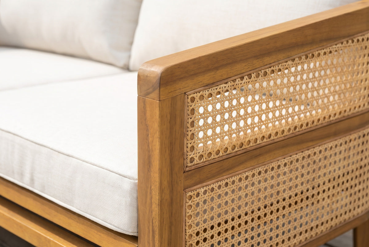 Close-up of the Filicudi sofa arm: honey acacia grain, woven rattan panel and the edge of the ivory seat cushion