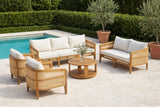 Filicudi acacia and rattan set on a limestone pool terrace at a Palm Beach villa, a clipped hedge and potted olive trees behind (vase and olive stems not included)