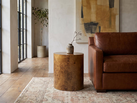 Fiumefreddo Walnut Burl Oval Pillar Side Table beside a leather sofa in an industrial loft