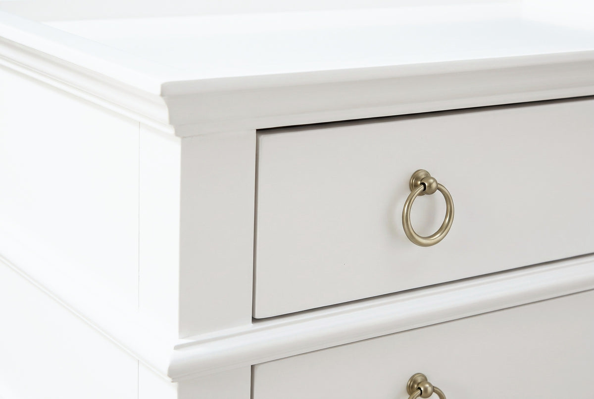 The corner of the white tray top of the Fonni nightstand with the upper drawer front and one brushed gold ring pull on a round mount