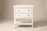 The Fonni nightstand, front view on a light studio backdrop: a tray top, two drawers with four brushed gold rings, moulded bands, square tapered legs and an open shelf