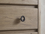 Close-up of the Fonzaso 66-Inch Weathered Knotty Oak 6-Drawer Dresser: a dark cast-iron oval ring pull on a knotty oak drawer front